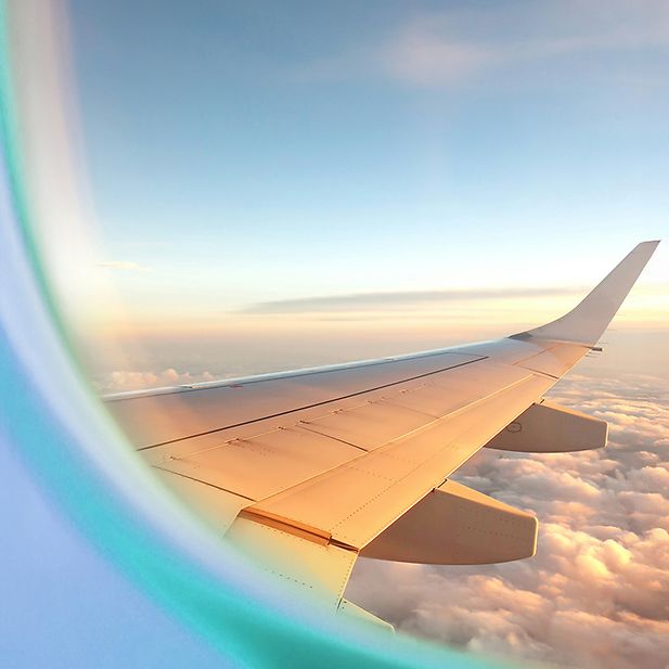 Vliegtuig in een heldere blauwe lucht met wolken.