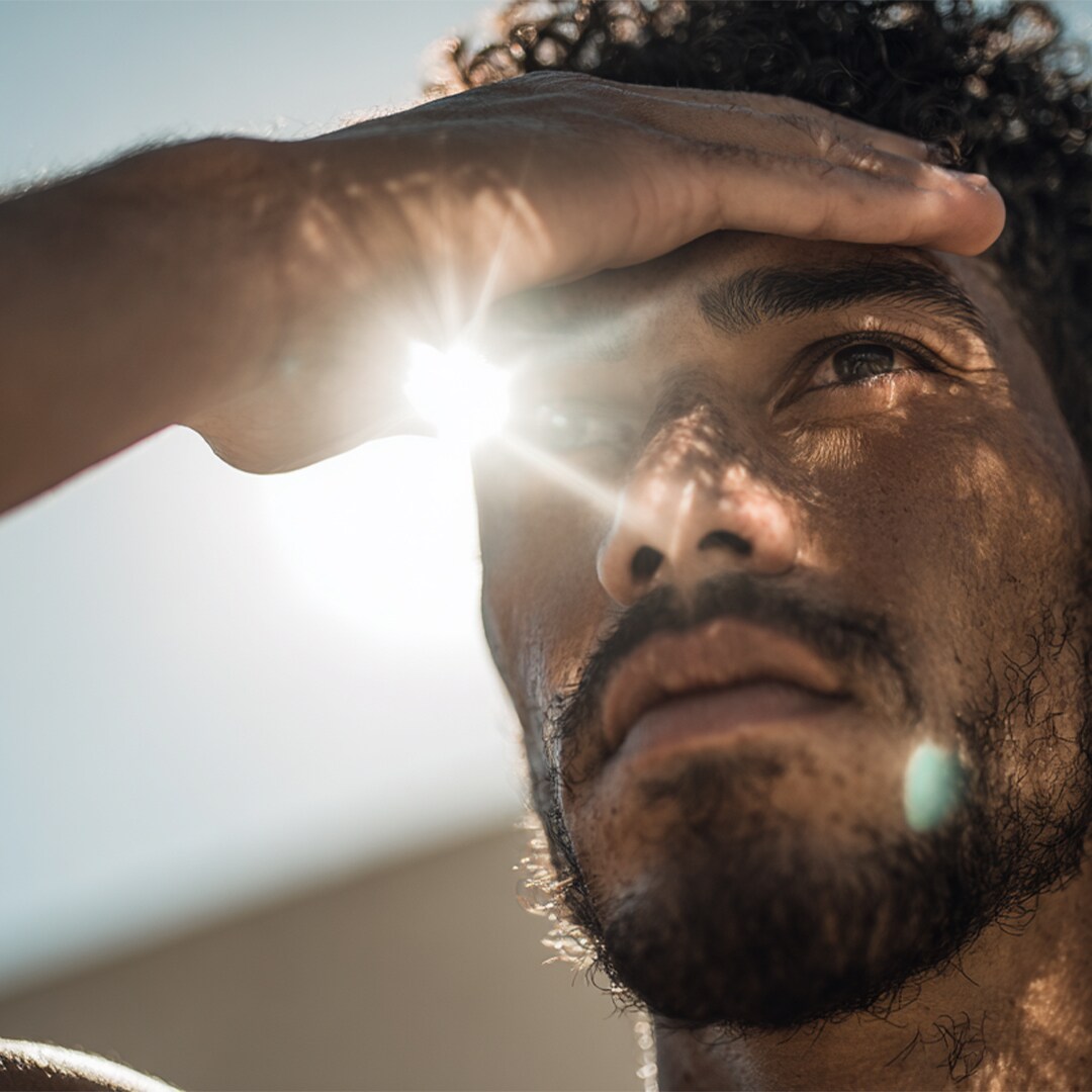 Man houdt zijn hand boven zijn ogen tegen fel zonlicht